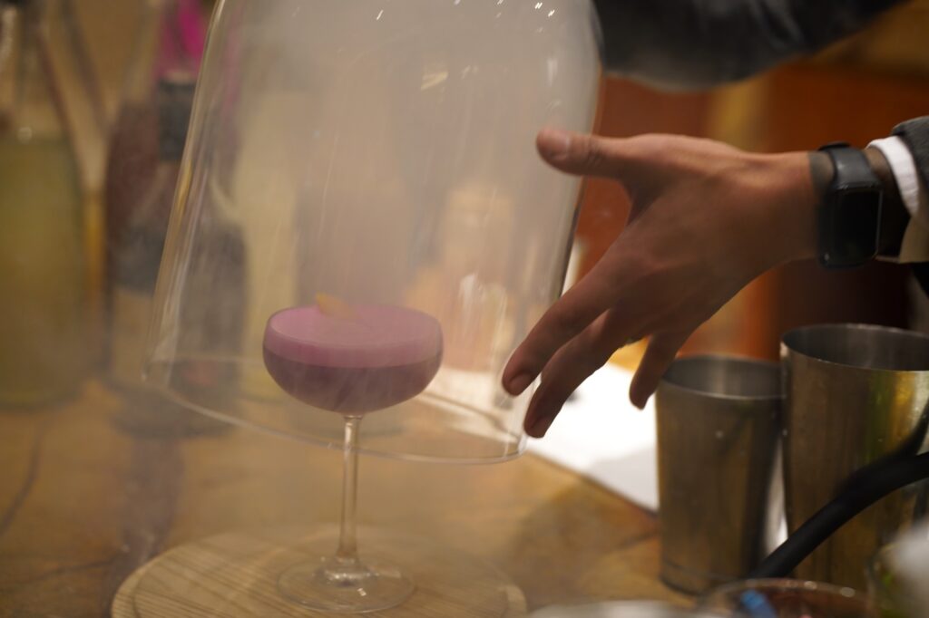 Hickory-smoked cocktail with blended scotch whiskey with dragonfruit juice, calamansi juice, sugar syrup, and egg white